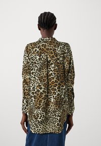 Camicia in stampa leopardata con vestibilità rilassata, maniche lunghe, colletto e orlo posteriore leggermente più lungo. Realizzata in tessuto morbido e leggero.