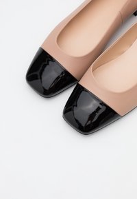 Beżowe baleriny z czubkiem w kształcie kwadratu z lakierowanej czarnej skóry. Górna część z gładkiej skóry, zaokrąglony kształt i miękkie beżowe wnętrze. Minimalistyczny styl.