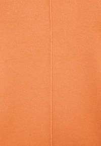 Oranje gebreide stof met een gladde textuur, met een centrale naad. Het algemeen ontwerp is eenvoudig met een uniforme kleur.