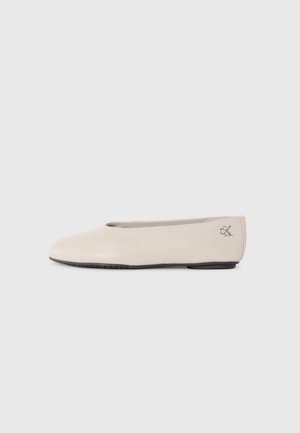 Beige Calvin Klein ballerina med rund tå og sort sål vist fra siden på hvid baggrund.