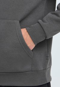 Felpa grigia con tasca a marsupio, polsini a coste e tessuto testurizzato. Ha una vestibilità comoda e dettagli di cucitura discreti all'orlo.