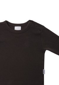 Braunes Langarm-Shirt aus weichem Stoff mit Rundhalsausschnitt. Verfügt über zwei Druckknöpfe an der Schulter und ein sichtbares Markenschild an der Seite.