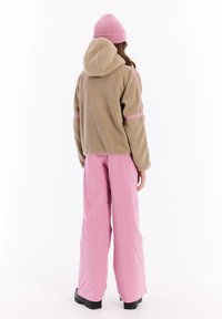 Beige fleece jack met capuchon en roze accenten, gecombineerd met roze waterdichte broek en zwarte schoenen. Soepele textuur met een losse pasvorm.