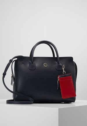 Sac à main en cuir noir avec deux poignées, une bandoulière amovible et un porte-cartes en cuir rouge attaché par un fermoir argenté.