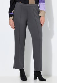 Szare spodnie o prostym kroju nogawki, z gładką teksturą i przeszyciami, zestawione z czarnymi botkami na obcasie za kostkę.