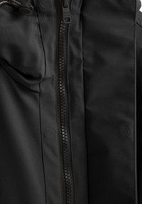 Giacca impermeabile nera con zip centrale, texture morbida e senza motivi o decorazioni visibili. Due dettagli di cucitura circolari.