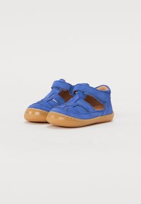 Scarpe in suede blu con una suola in gomma tan flessibile, dotate di cinturini in Velcro e design forati per la traspirabilità.