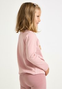 Lyserød langærmet skjorte i blødt stof med broderet design. Sættes sammen med matchende lyserøde leggings med glat tekstur.