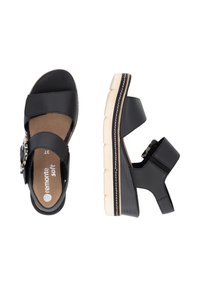 Sandales compensées en cuir noir avec deux larges lanières et une boucle décorative. Semelle intérieure rembourrée, plateforme texturée et semelle de teinte neutre.