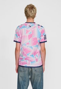 Kurzarm-Sportshirt in Pink und Blau mit geometrischem Muster. Verfügt über einen marineblauen Kragen und kontrastierende marineblaue Ärmelakzente.