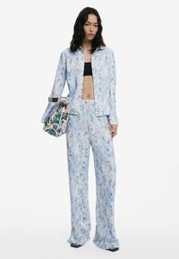 Ensemble composé d'un haut bleu clair à motifs et d'un pantalon large, fabriqué dans un tissu doux. Un design floral rehausse l'ensemble. Comprend un sac à main imprimé en tant qu'accent.