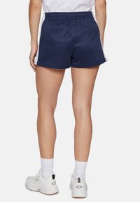 Navy blue pinstriped shorts with an elastic waistband, paired with white athletic socks and white sneakers. Visible back design accents.