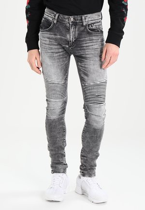 Jeans skinny grises con patrón de rayas horizontales en las rodillas, detalles desgastados, cinco bolsillos y herrajes en tono plateado.