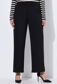 Zwarte wijde broek met een soepele textuur, elastische tailleband en voorkruiden, gecombineerd met zwarte hoge hakken en een gestreept topje.