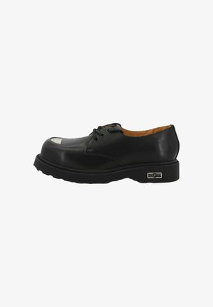 Scarpa derby in pelle nera con punta arrotondata, suola in gomma e un distintivo accento bianco sulla tomaia. Caratterizzata da chiusura con lacci.