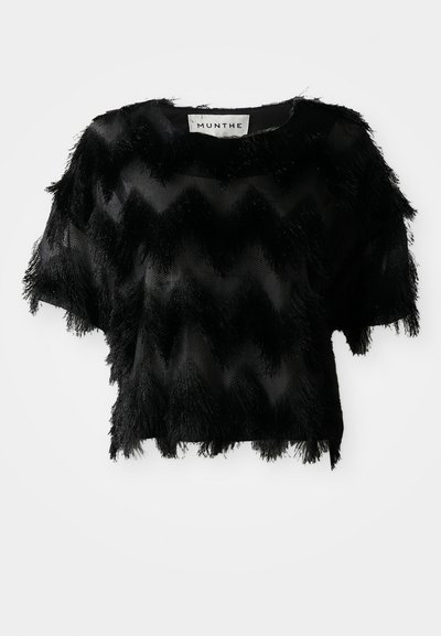 Must have lühikeste varrukatega must pehme särk, millel on tekstuuriga sakilised jooned ja fringi detailid ääres ning varrukatel. Materjal näib olema kerge ja läbipaistev.