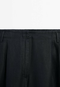 Pantalons noirs à coupe décontractée, avec une texture lisse, des poches latérales et une taille partiellement élastique pour plus de confort.