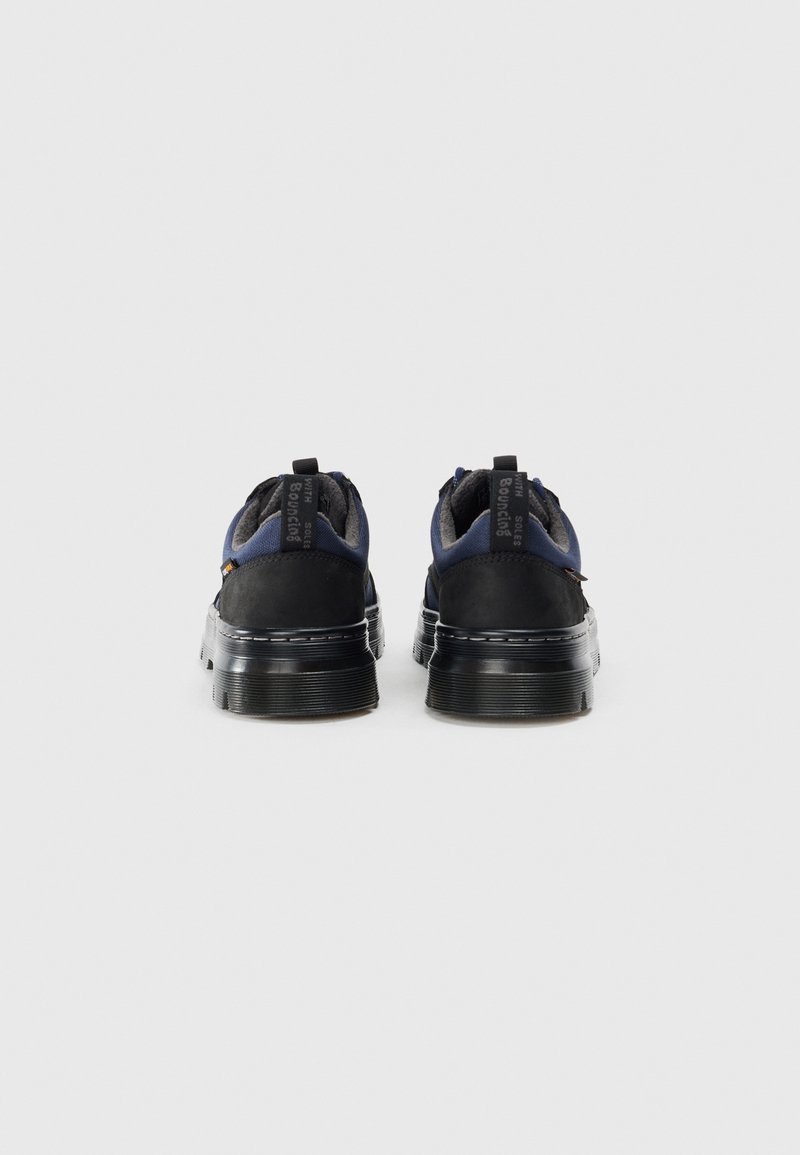 Sort og marineblå sneaker med tekstureret overdel, polstret indvendig og en tyk, ribbet sål. Har trækketab og logo-accenter på hælen.