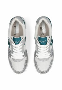 Baskets blanches avec des accents en paillettes argentées, empeigne en mesh, logo turquoise sur la languette et lacets blancs. Semelle plate pour le confort.