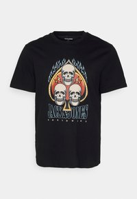 Camiseta de algodón negra con un gráfico central de tres calaveras dentro de un as de picas, acentuado por llamas y un texto en negrita abajo.
