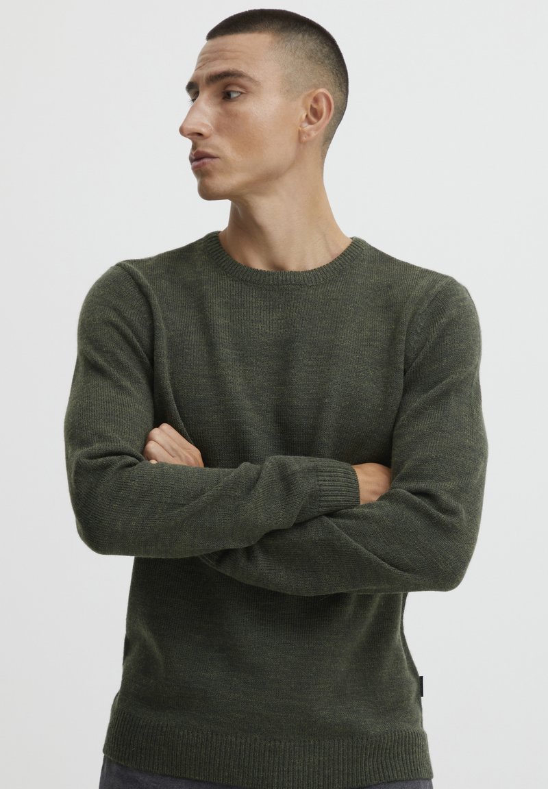 Dunkelgrüner Strickpullover, Rundhalsausschnitt, gerippte Bündchen und Saum, strukturierter Stoff, taillierte Silhouette, geeignet für Freizeitkleidung.