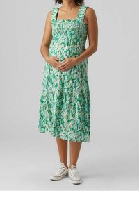 Zelené a bílé midi šaty s vzorem, čtvercovým výstřihem, širokými ramínky a elastickým žebrováním. Oblečené s bílými teniskami. Měkká, splývavá látka.