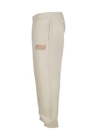 Beige joggebukser laget av mykt stoff, med elastisk midje, sidelommer og en subtil oransje logo på venstre ben.