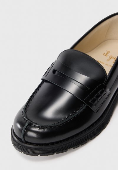Svart skinnloafers med en jevn finish, en sømdetalj og et hevet bånd over vampsen. Teksturert gummi såle for godt grep.