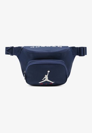 Banane bleu marine en tissu résistant, avec une poche zippée à l'avant, un logo Jumpman brodé et le texte « AIR » en rouge.