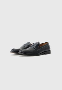 Black leather loafers with a smooth finish, decorative stitching, and a low heel. Features a classic design and a slightly rounded toe.