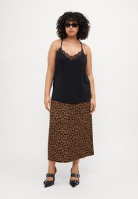 Svart camisol med blondekanter kombinert med et leopardmønstret maxiskjørt. Modellen har på seg svarte spisse hæler og slanke solbriller.