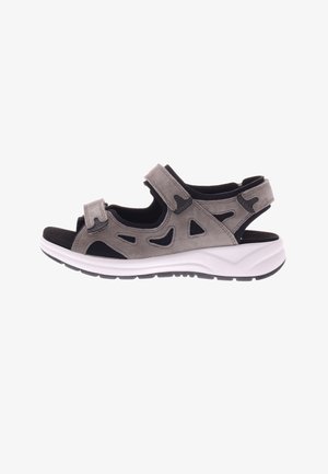 Grijze suède sandaal met uitgesneden ontwerpen, dubbele klittenbandsluitingen en een witte zool met zwarte loopzool voor grip. Open achterkant voor ademend vermogen.