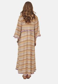 Largo vestido estampado con mangas de campana, que presenta colores alternos de beige, marrón y lavanda. Detalle texturizado en el dobladillo.