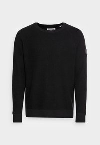 Pull noir en tricot avec col rond, poignets et ourlet côtelés, manches raglan et une petite étiquette logo en tissu sur le haut du bras.