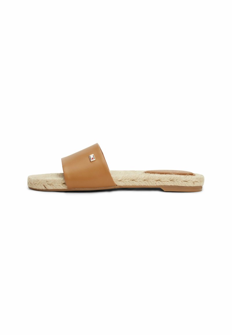 Sandale marron à glissière avec large bride en cuir, semelle en jute tressé et petit logo en métal rectangulaire sur la bride, présentée en profil latéral.