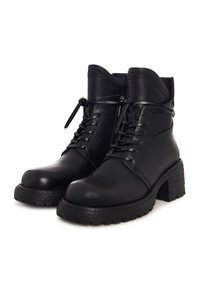 Bottines en cuir noir avec talons épais, lacets sur le devant et fermetures éclair latérales sur fond blanc.