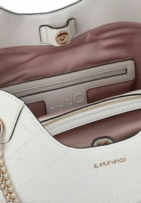 Borsa bianca con texture e hardware dorato, dotata di fodera rosa e tasca interna con zip. Logo in rilievo all'interno.