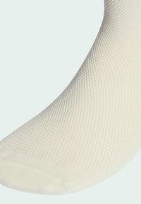 Jasno-beżowa skarpetka z teksturowanej dzianiny. Posiada gładki palec oraz prążkowany ściągacz zapewniający pewne dopasowanie.