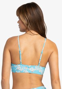 Blå blomsterbikini topp med justerbare stropper, blomsterdesign, og en glatt tekstur. Designet for komfort med en tettsittende passform.
