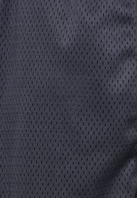 Mörkgrå nätväv med ett rutmönster av små perforeringar, som visar en ventilerande textur lämplig för sportkläder.