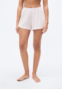 Shorts de détente rose clair en tissu doux et texturé, avec une taille élastique et une coupe ample, idéaux pour un port confortable.