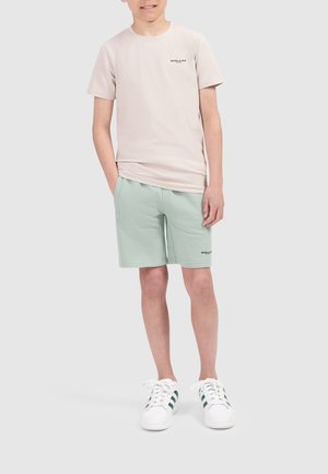 Helles beiges T-Shirt mit dem Text "BALLIN", kombiniert mit mintgrünen Shorts. Weiße Sneakers mit grünen Streifen. Einfaches, lässiges Design.