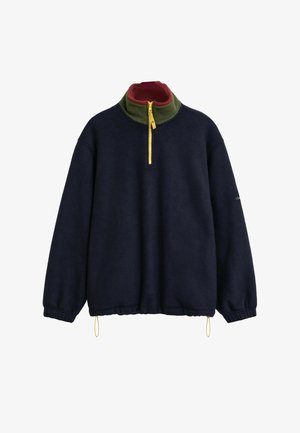 Marineblauwe fleece-pullover met hoge kraag, voorzien van een groene binnenvoering en een gele rits. Elastische mouwen en een trekkoord onderkant.