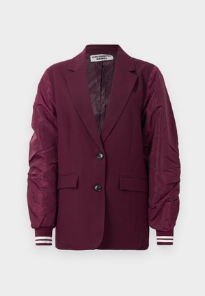 Burgundowy żakiet z dzianinowymi rękawami w stylu bomber, dwoma czarnymi guzikami, klapami, przednimi kieszeniami z klapką oraz detalami w paski na mankietach.