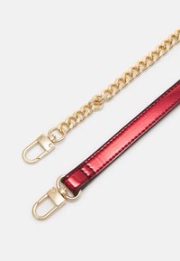 Bracelet à maillons en chaîne dorée associé à une bande texturée brillante rouge et noire. Dispose de fermoirs métalliques aux deux extrémités pour fixation.