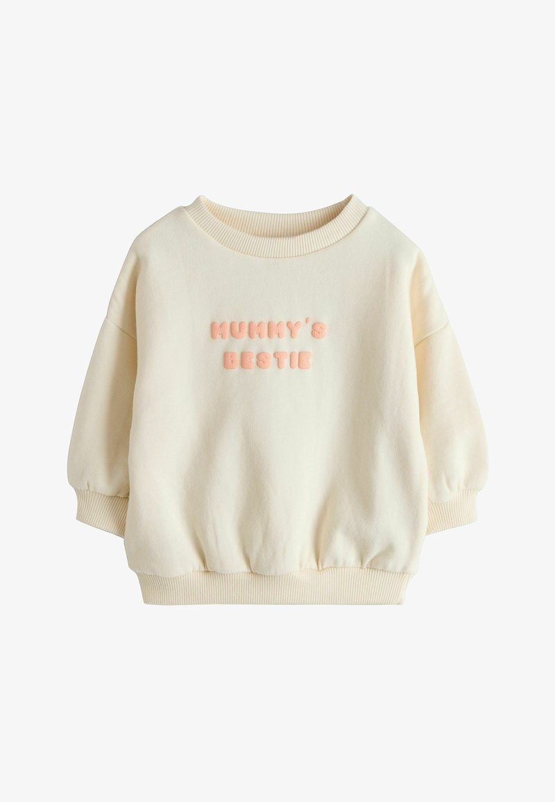 Sweatshirt pour tout-petit couleur crème avec poignets et ourlet côtelés, affichant un texte rose en relief « MUMMY'S BESTIE » sur la poitrine.