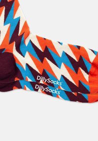 Bunte Socken mit einem Zickzackmuster in Orange, Blau, Weiß und Kastanienbraun, mit verstärktem Fersen- und Zehenbereich. Markenname an der Seite aufgedruckt.