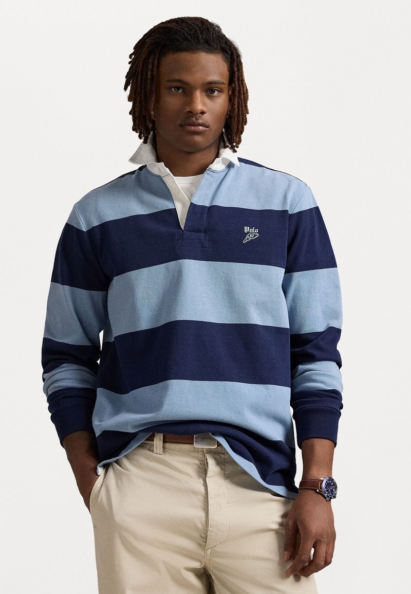 Blauwe en marineblauwe gestreepte langemouwen polo met een kraag en logo-detail. Draag over een witte laagjesshirt, ter aanvulling op kaki broek.