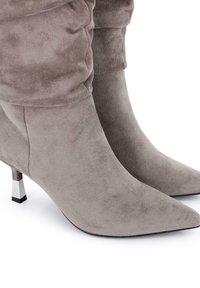 Botas de tobillo de ante gris con punta afilada, que presentan un diseño arrugado y un tacón de bloque plateado para contraste y mayor estabilidad.