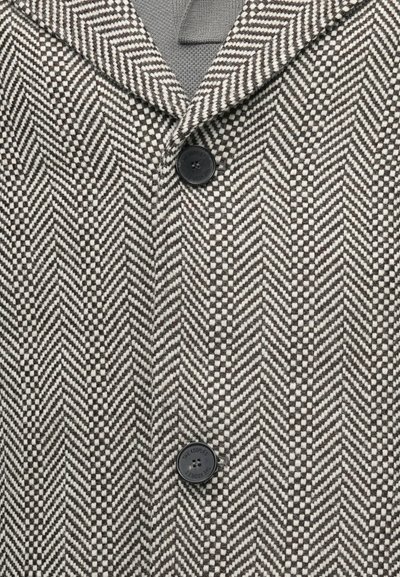 Kaput s uzorkom riblje kosti u crnoj i bijeloj boji, s reverjastim ovratnikom i crnim dugmetom za zatvaranje. Teksturirani vune.